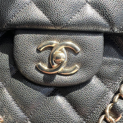 Close-up of a black quilted handbag with a silver Chanel logo.