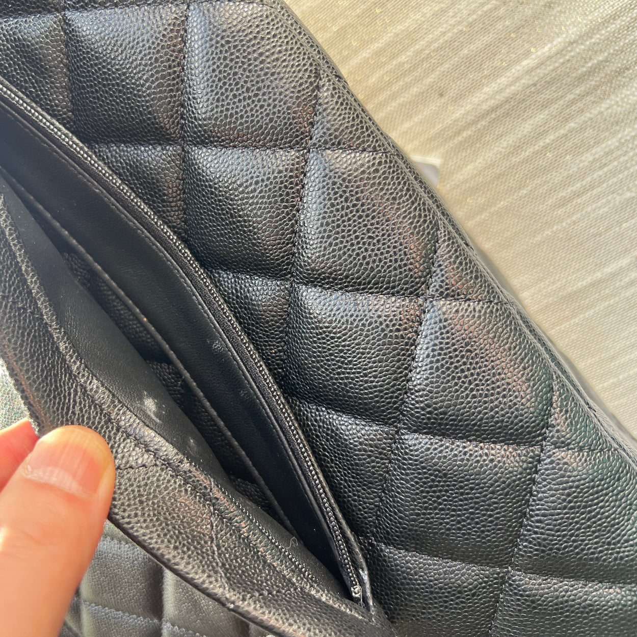 Gray quilted leather wallet held by a hand against a neutral background