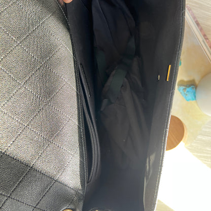 Gray quilted handbag with a hand holding open the flap, showing the interior.