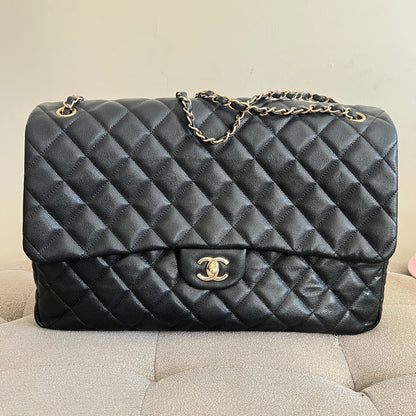 Black quilted handbag with gold chain on a beige surface