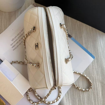 Beige handbag with gold chain on a surface with a book and plant in the background