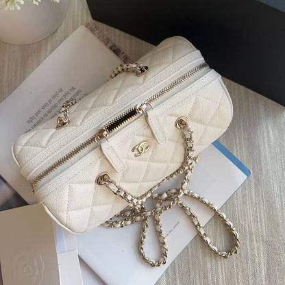 Quilted cream handbag with gold chain on a surface with books and flowers.