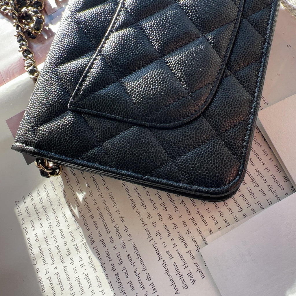 Black quilted handbag on top of a book with 'Chanel' branding.