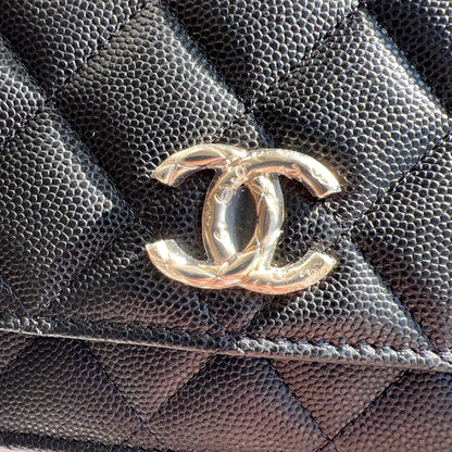 Gold Chanel logo on a black quilted leather surface
