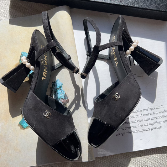 Black high-heeled sandals with pearl embellishments on a magazine page