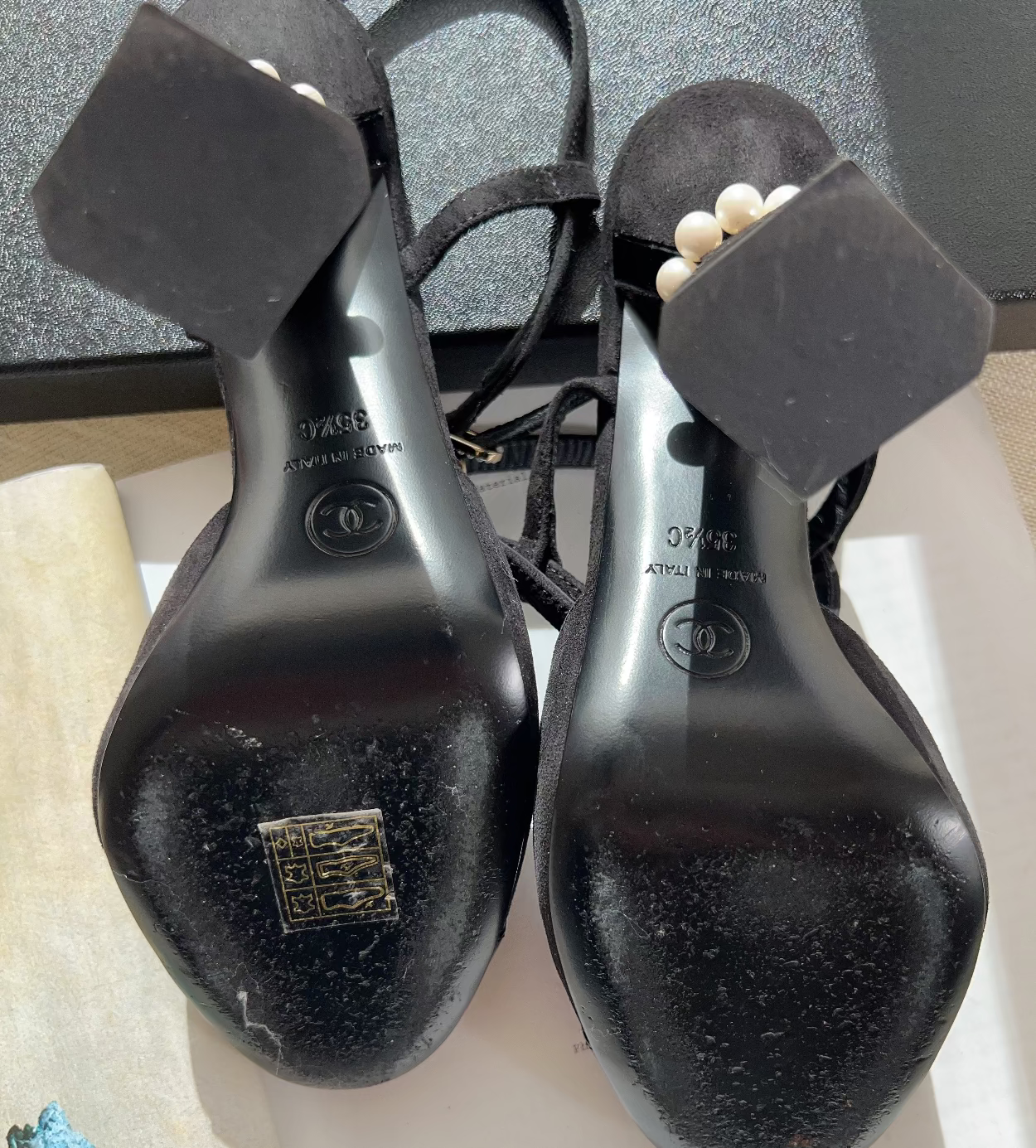 Pair of black high-heeled shoes with visible brand logo on a light background