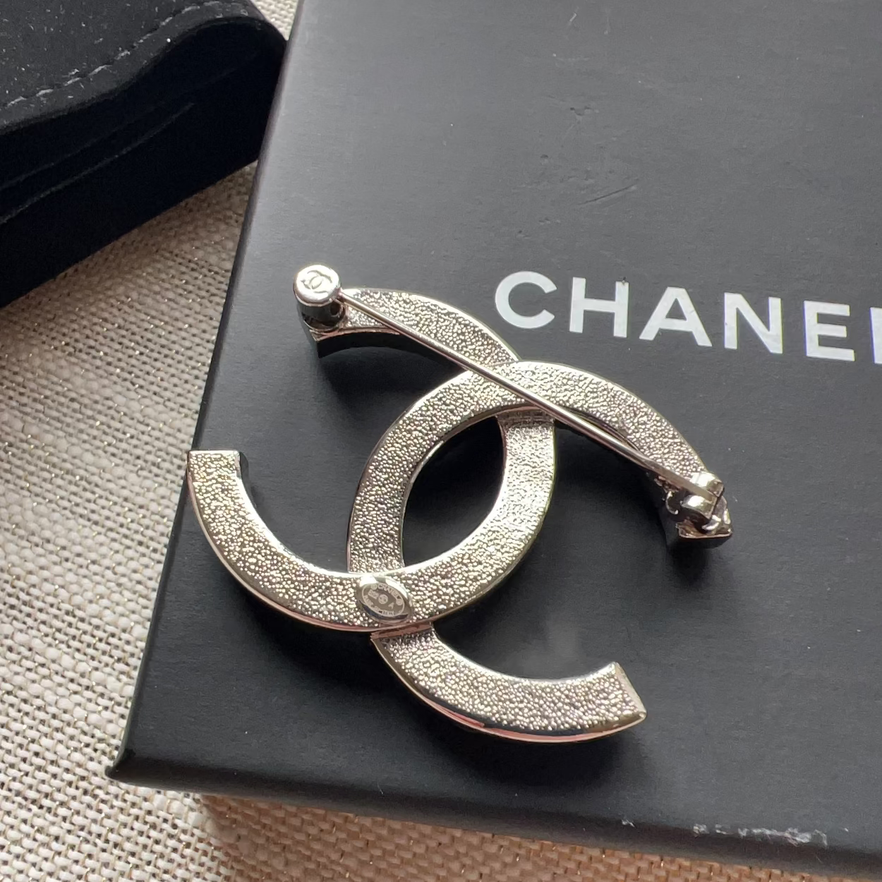 Chanel brooch on a black box with 'Chanel' branding
