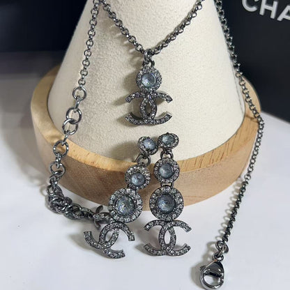 Chanel jewelry set with necklace and earrings on a wooden stand.