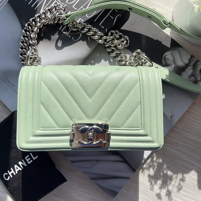 Mint green quilted handbag with chain strap on a surface with a Chanel box.