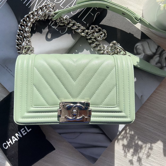 Mint green quilted handbag with chain strap on a surface with a Chanel box.
