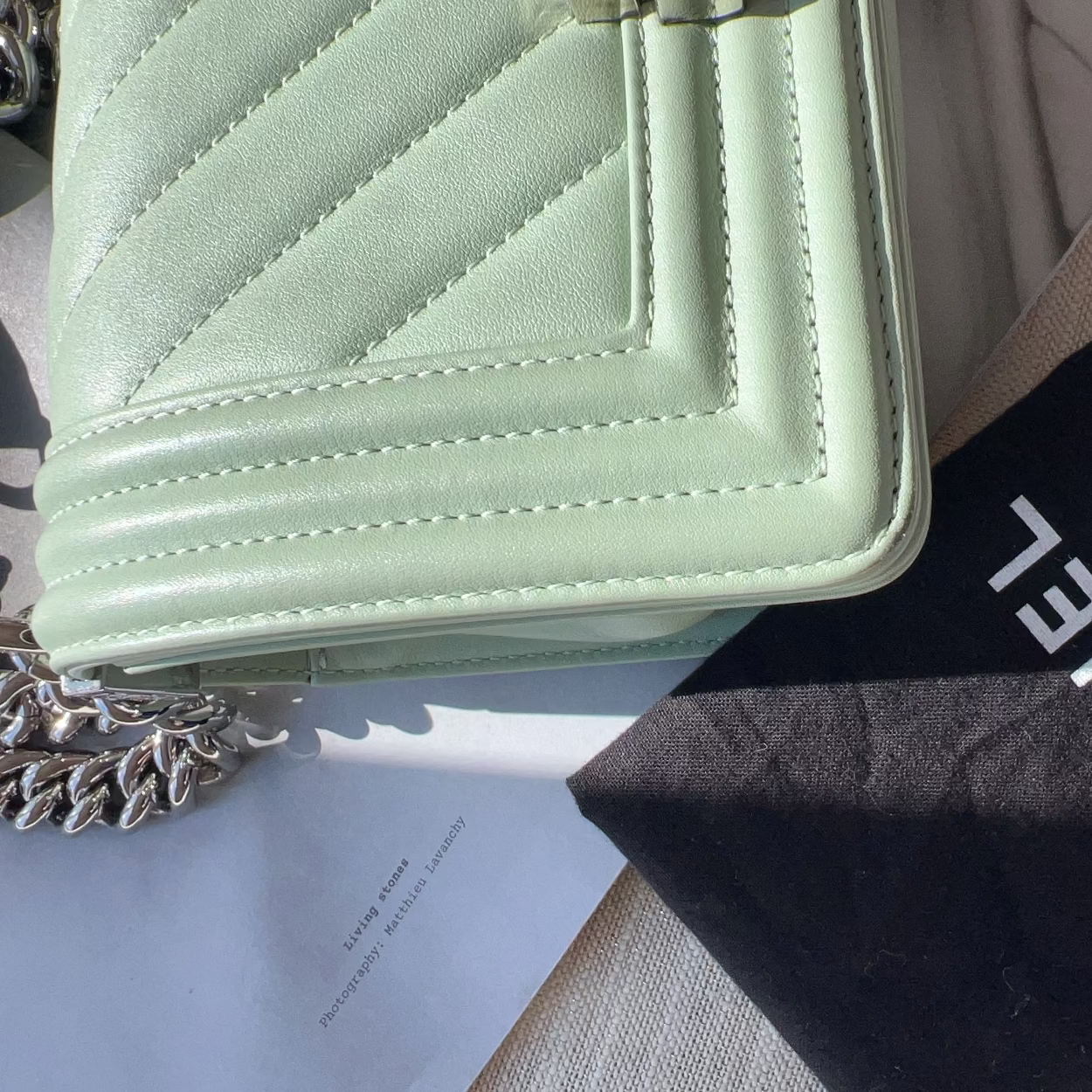 Light green quilted handbag with a Chanel logo on a black mat