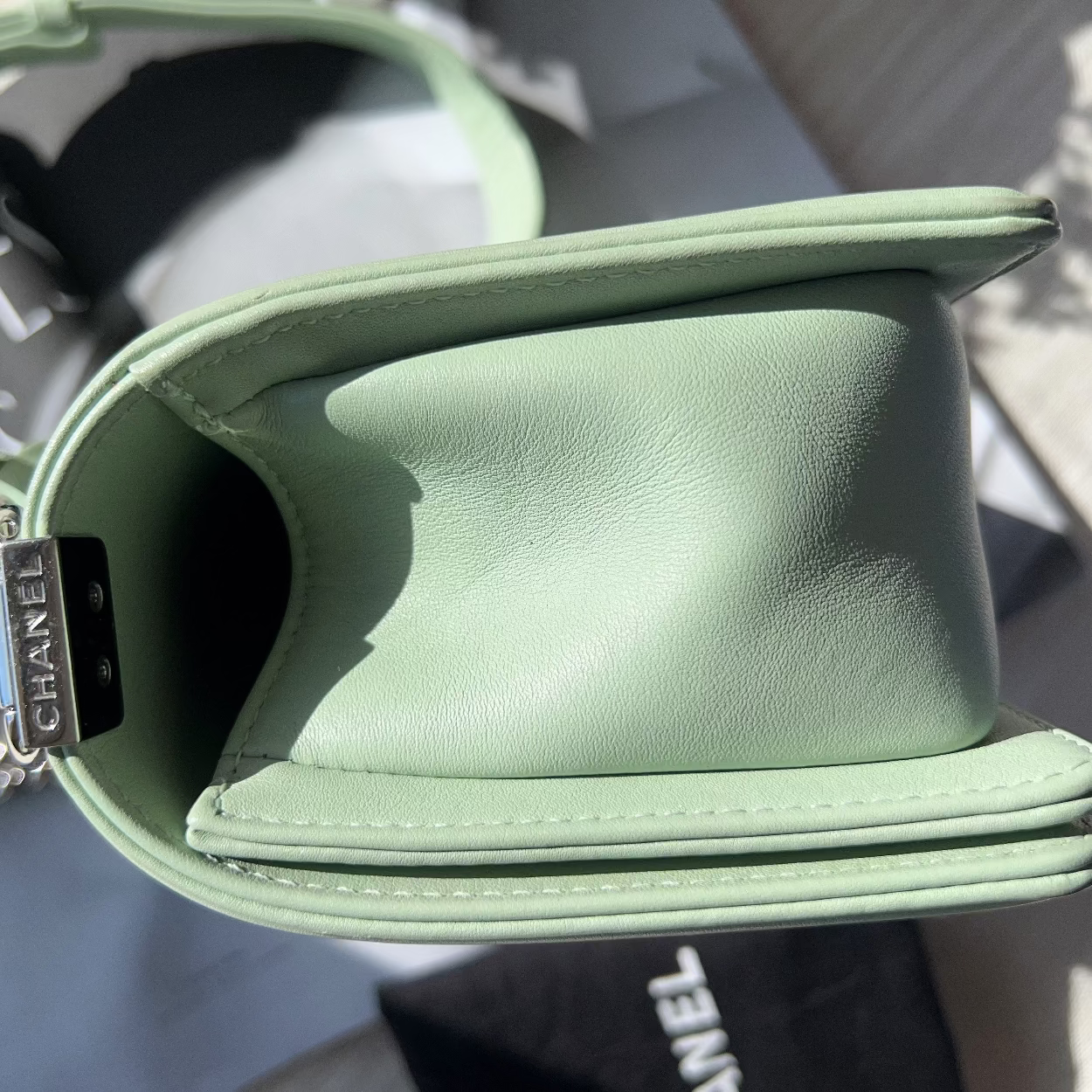 Green handbag with Chanel logo on a blurred background