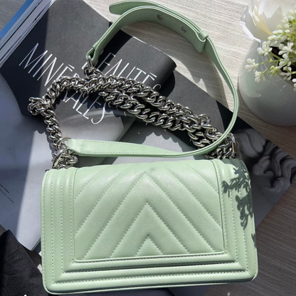 Light green handbag with chain handle on a surface with a magazine underneath