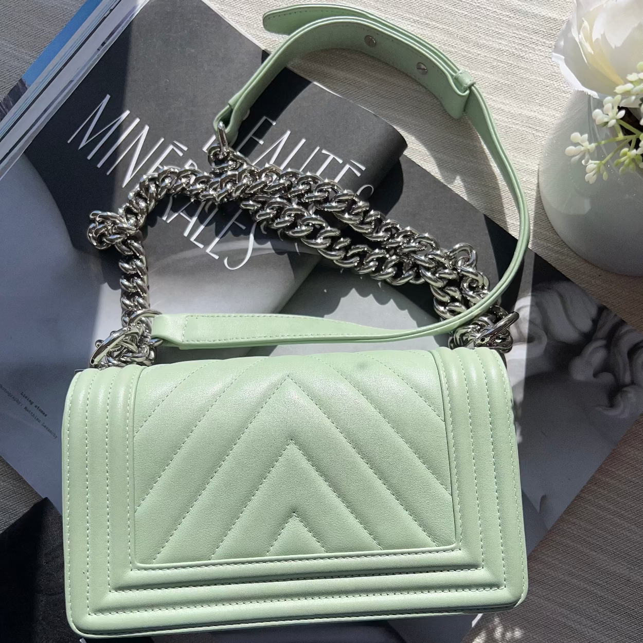 Mint green handbag with chain detail on a magazine