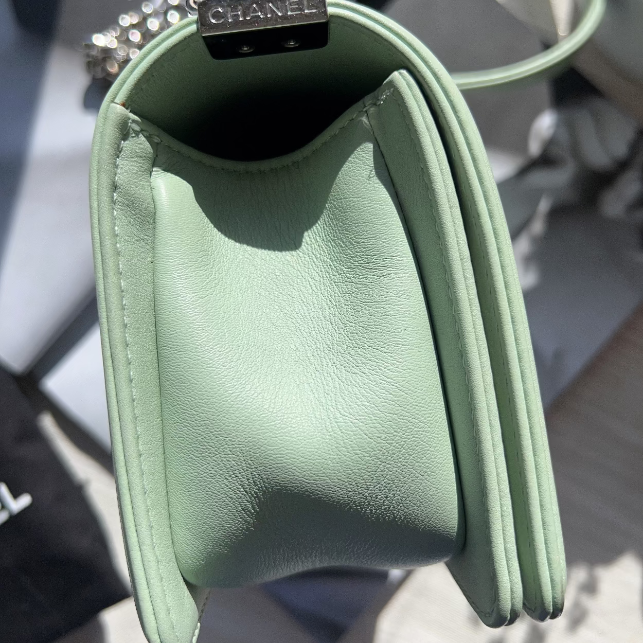 Green leather handbag with Chanel logo on a blurred background