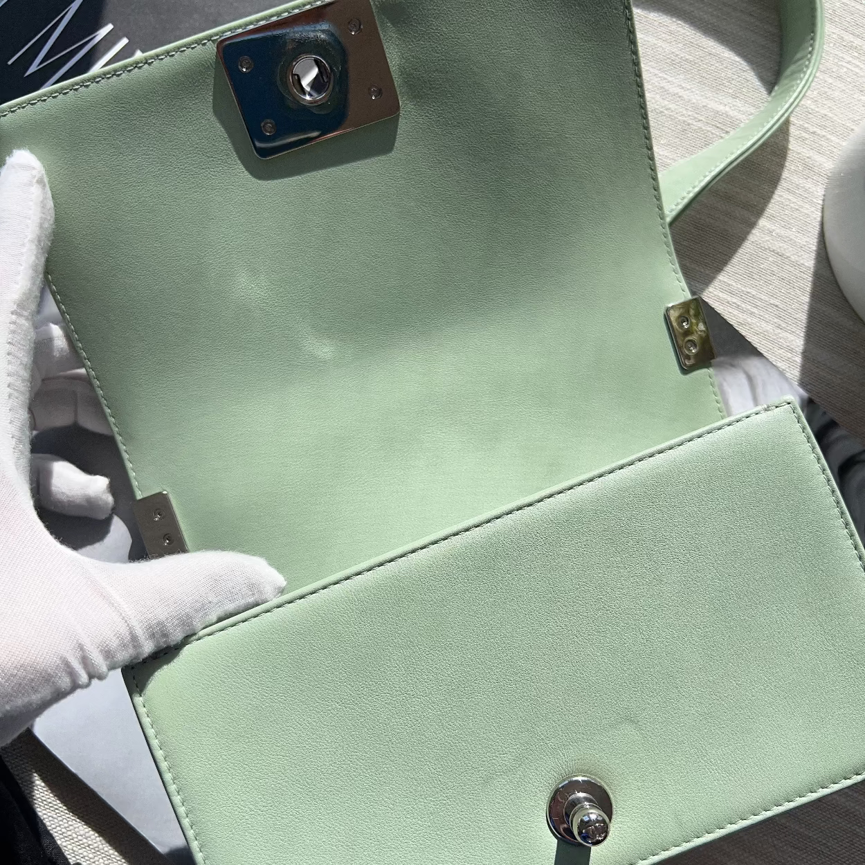 Light green handbag with gold accents on a wooden surface