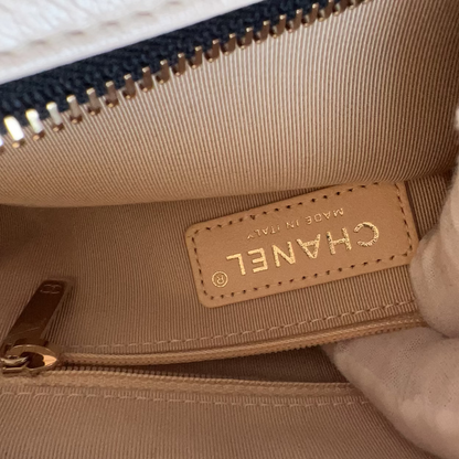 Close-up of a beige Chanel handbag with a gold zipper.