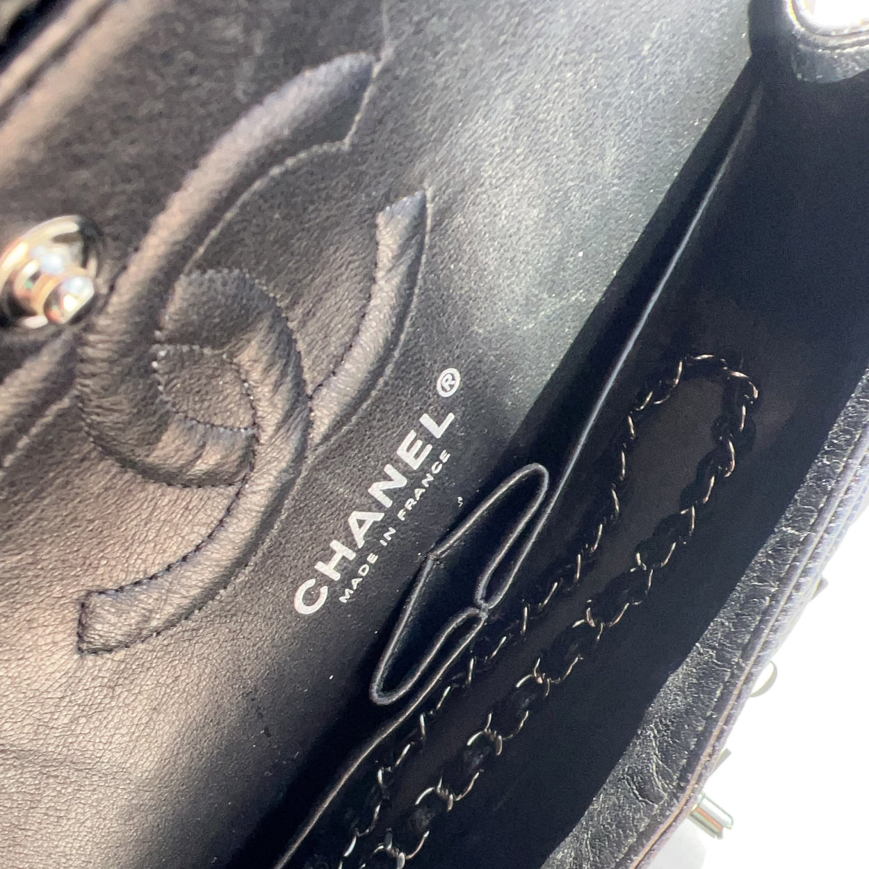 Close-up of a Chanel handbag with floral design and chain detail.