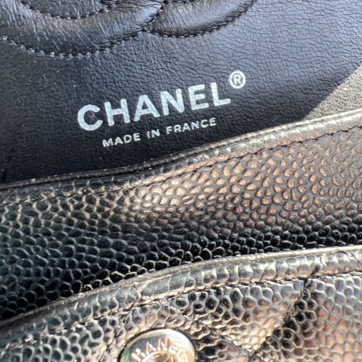 Close-up of Chanel logo and 'Made in France' text on a black leather surface.