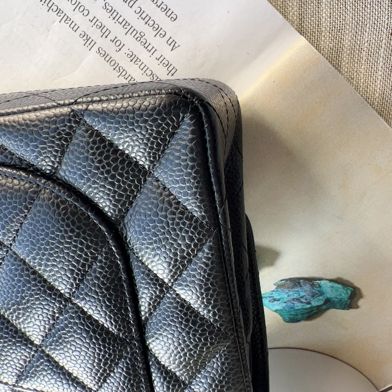 Black quilted leather wallet on an open book with a green stone