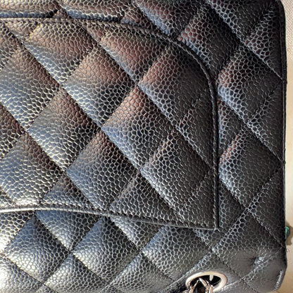 Black quilted handbag with chain detail on a light background