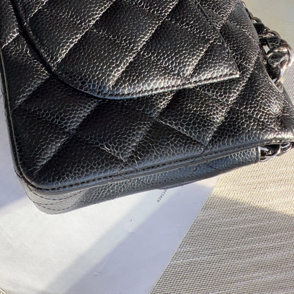 Black quilted handbag on a textured surface with text in the background
