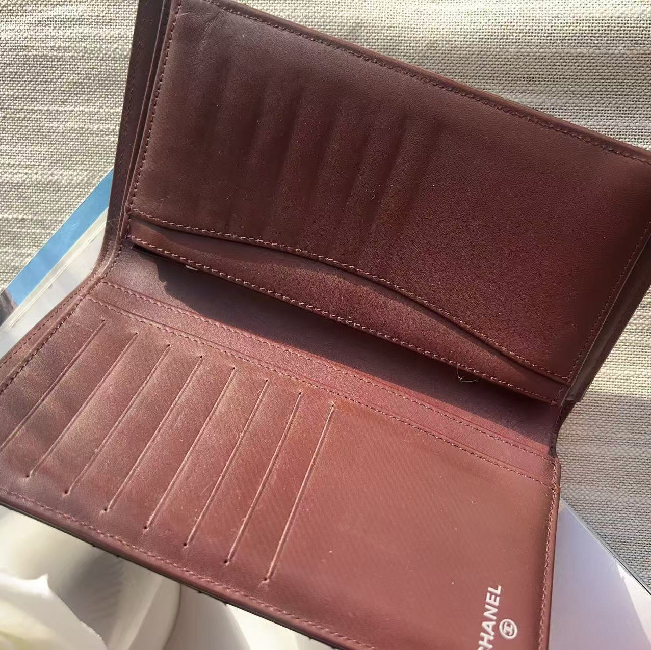 Brown leather wallet with Chanel logo on a textured surface