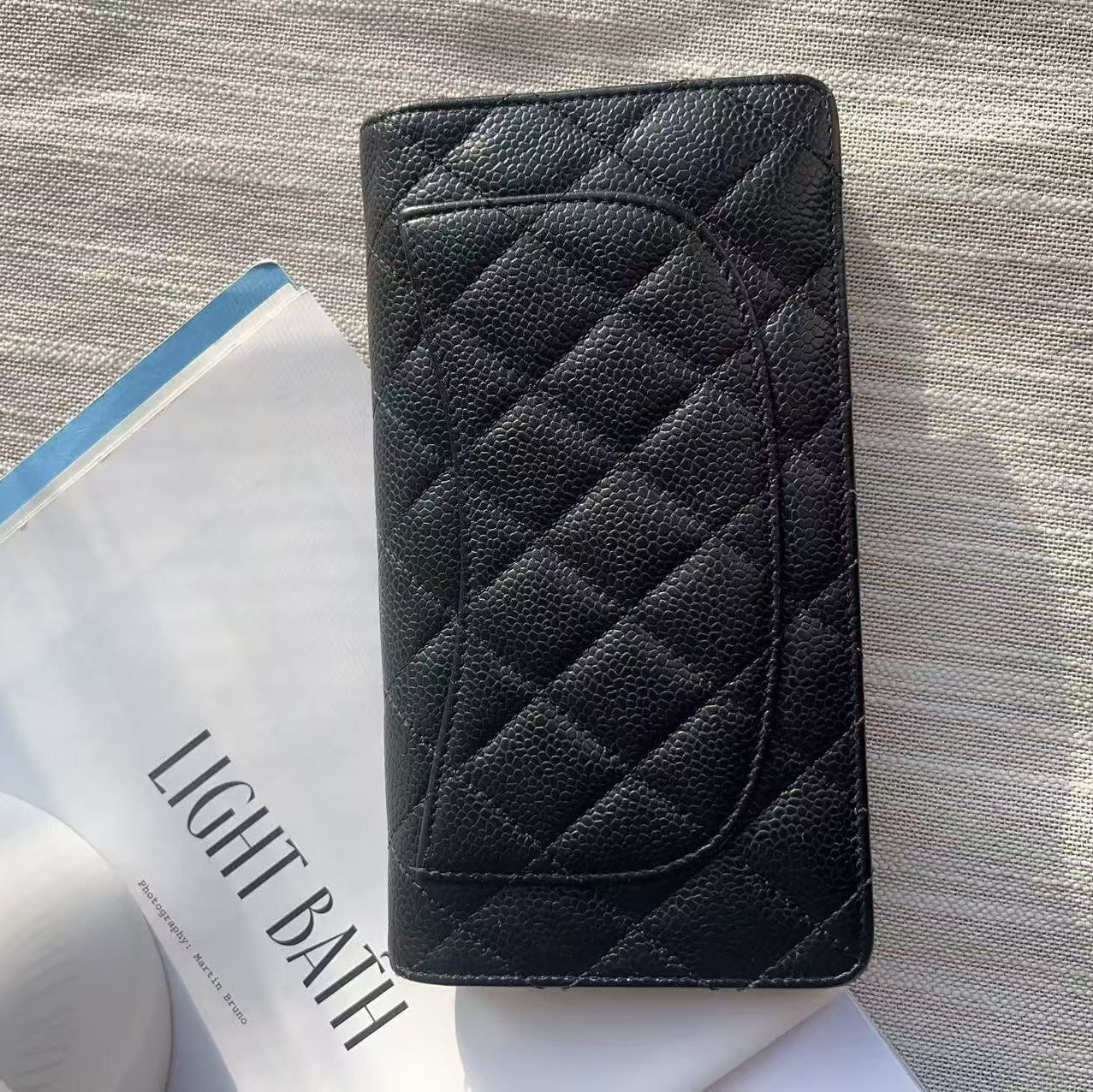 Black quilted wallet on a textured surface with a magazine underneath