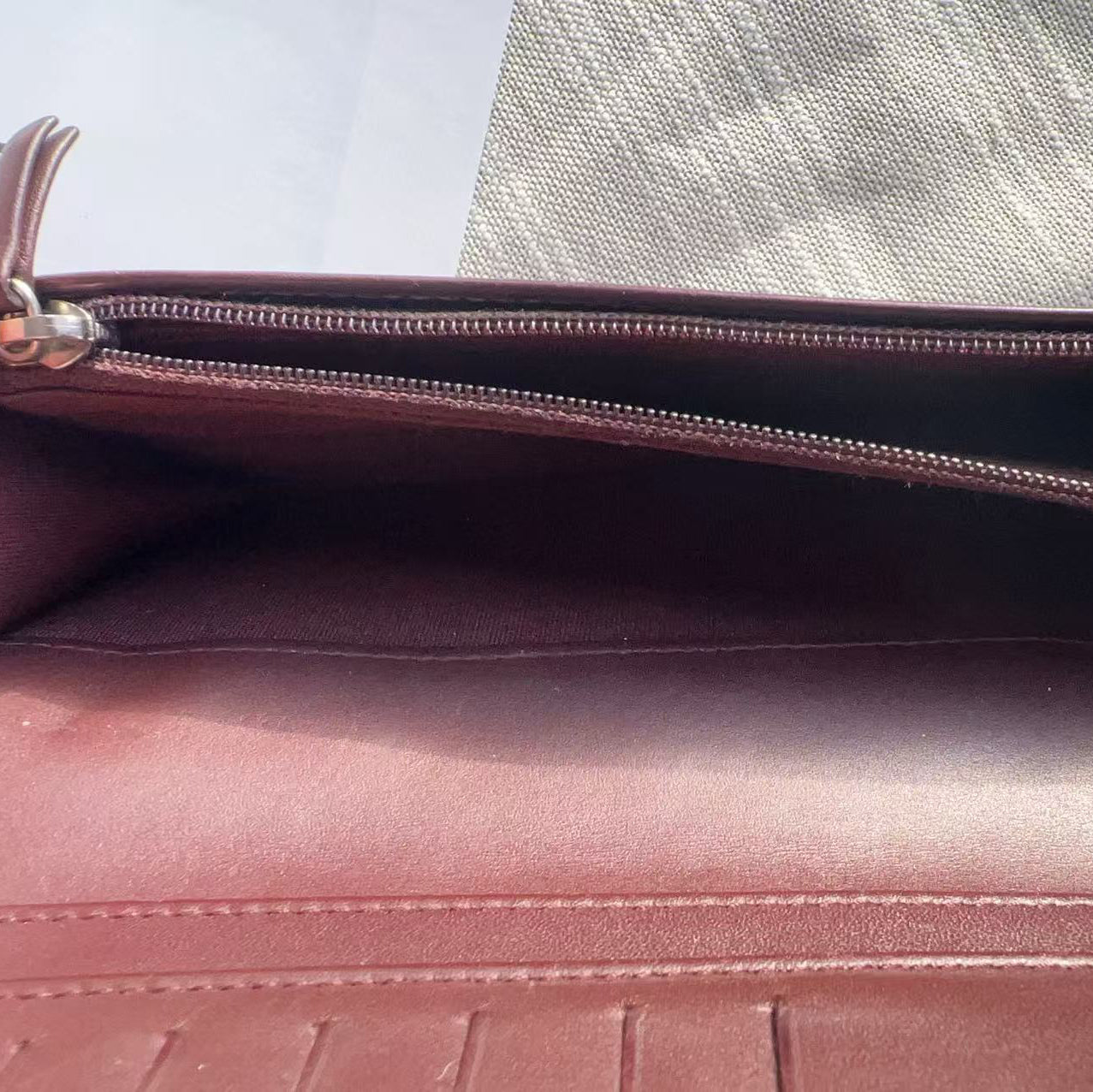 Brown leather clutch bag with a zipper on a light gray background