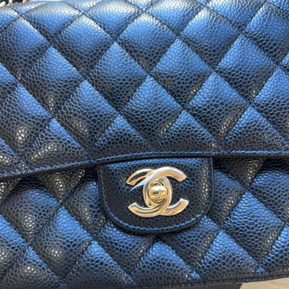 A close-up of a blue quilted leather handbag with a gold-tone interlocking CC turn-lock clasp, showing the textured pebbled leather and diamond-quilted pattern.
