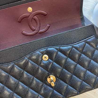 Close-up of a luxury handbag interior showing a black pebbled leather quilted flap with gold-tone hardware and a burgundy leather interior with an embossed interlocking CC logo, indicating Chanel.