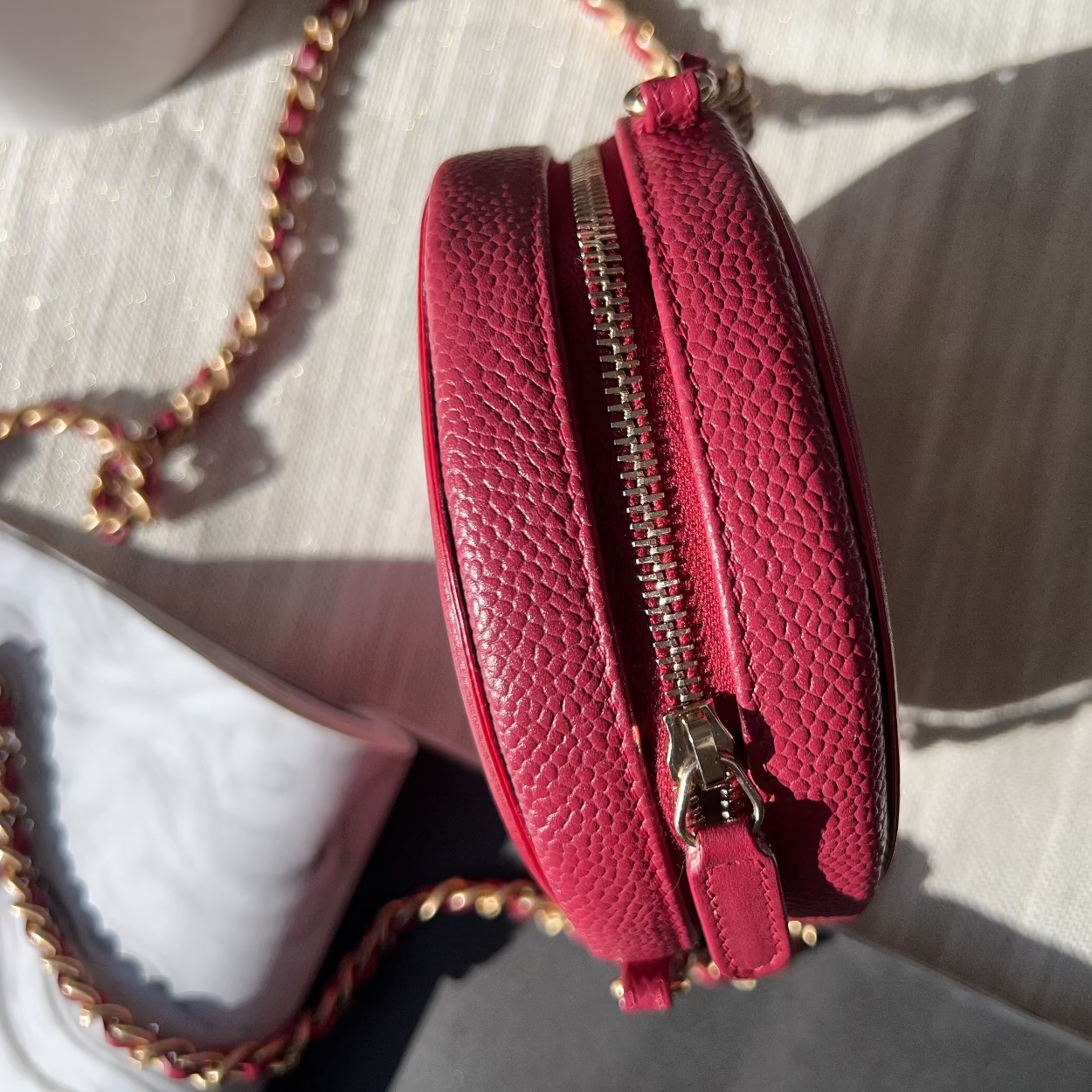 Red textured handbag with gold zipper on a light background