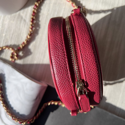 Red textured handbag with gold zipper on a light background