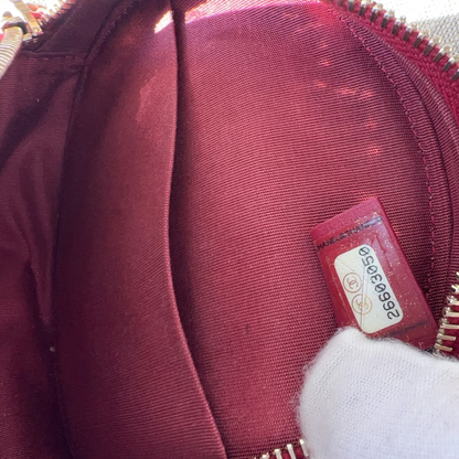 Close-up of a maroon bag with a visible brand label on a textured surface.