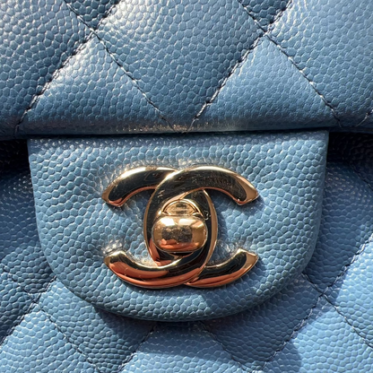 Close-up of a blue quilted handbag with a gold Chanel logo.