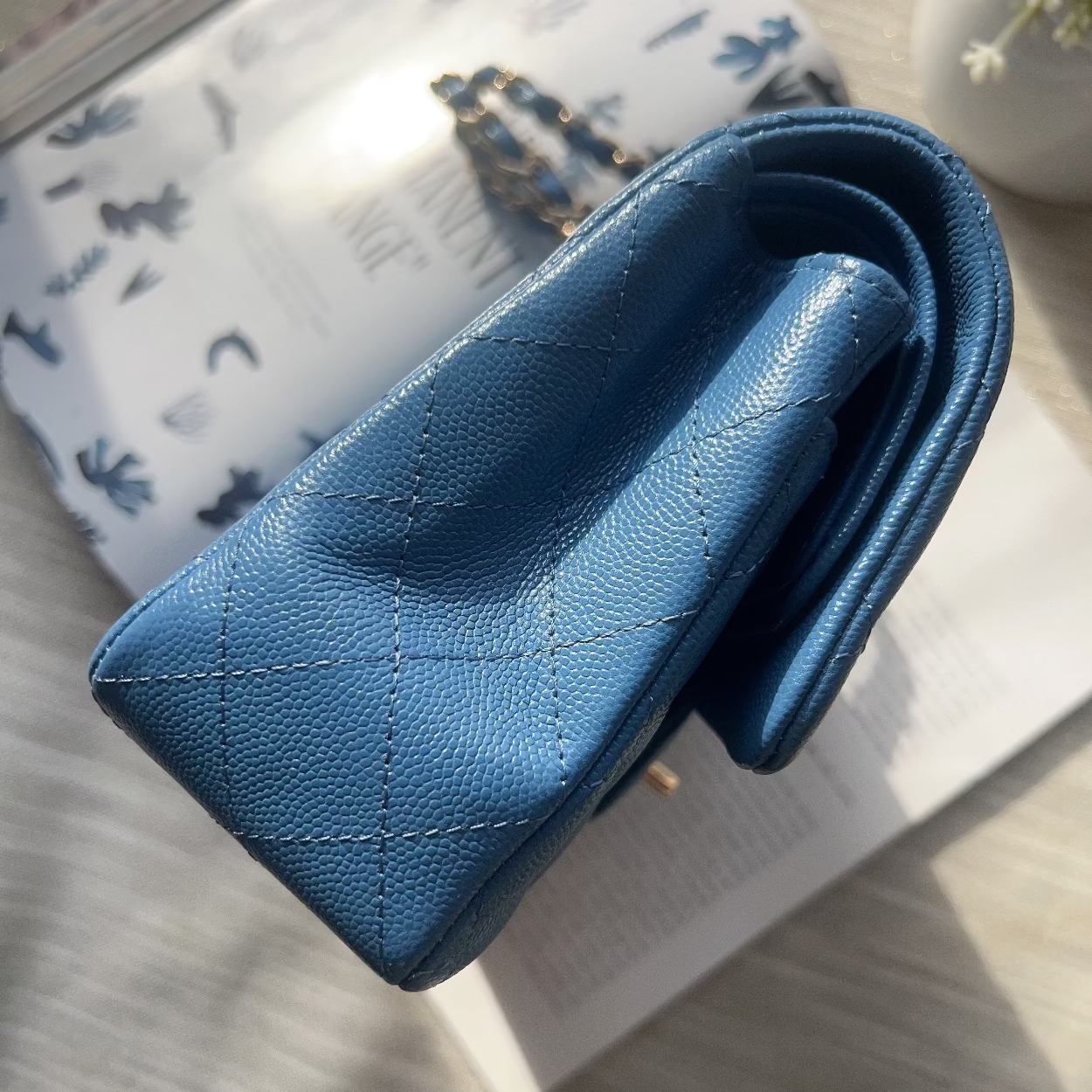 Blue leather wallet on a light surface with a patterned book in the background