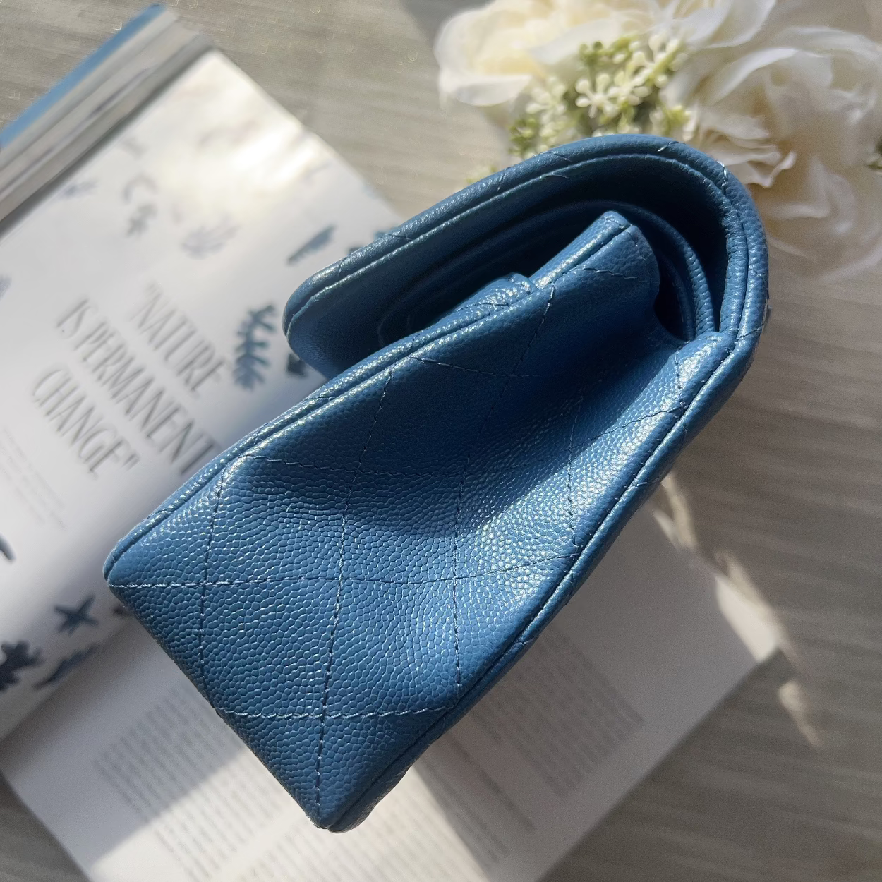 Blue wallet on an open book with white flowers in the background