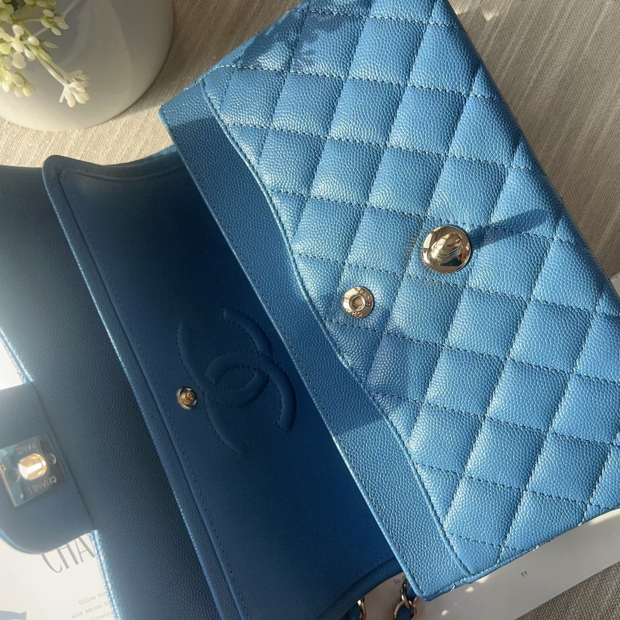 Blue quilted handbag with gold buttons on a wooden surface