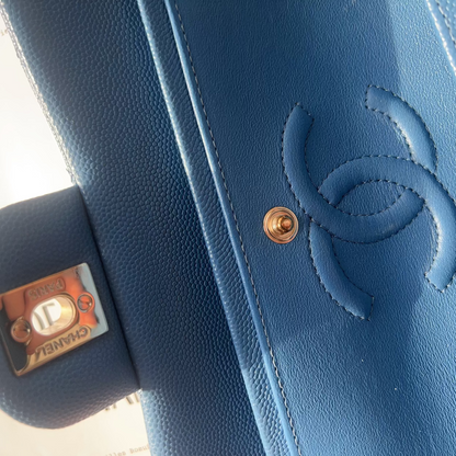 Close-up of a blue Chanel handbag with gold hardware on a patterned background