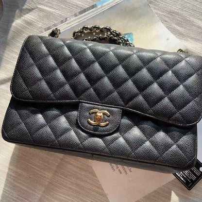 A black quilted leather handbag with a gold-tone interlocking CC logo clasp, resting on a light-colored surface with papers underneath.