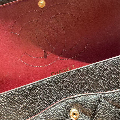 Close-up of a Chanel handbag interior showing a dark brown pebbled leather exterior, a deep red interior lining, and an embossed Chanel logo with gold-tone hardware.