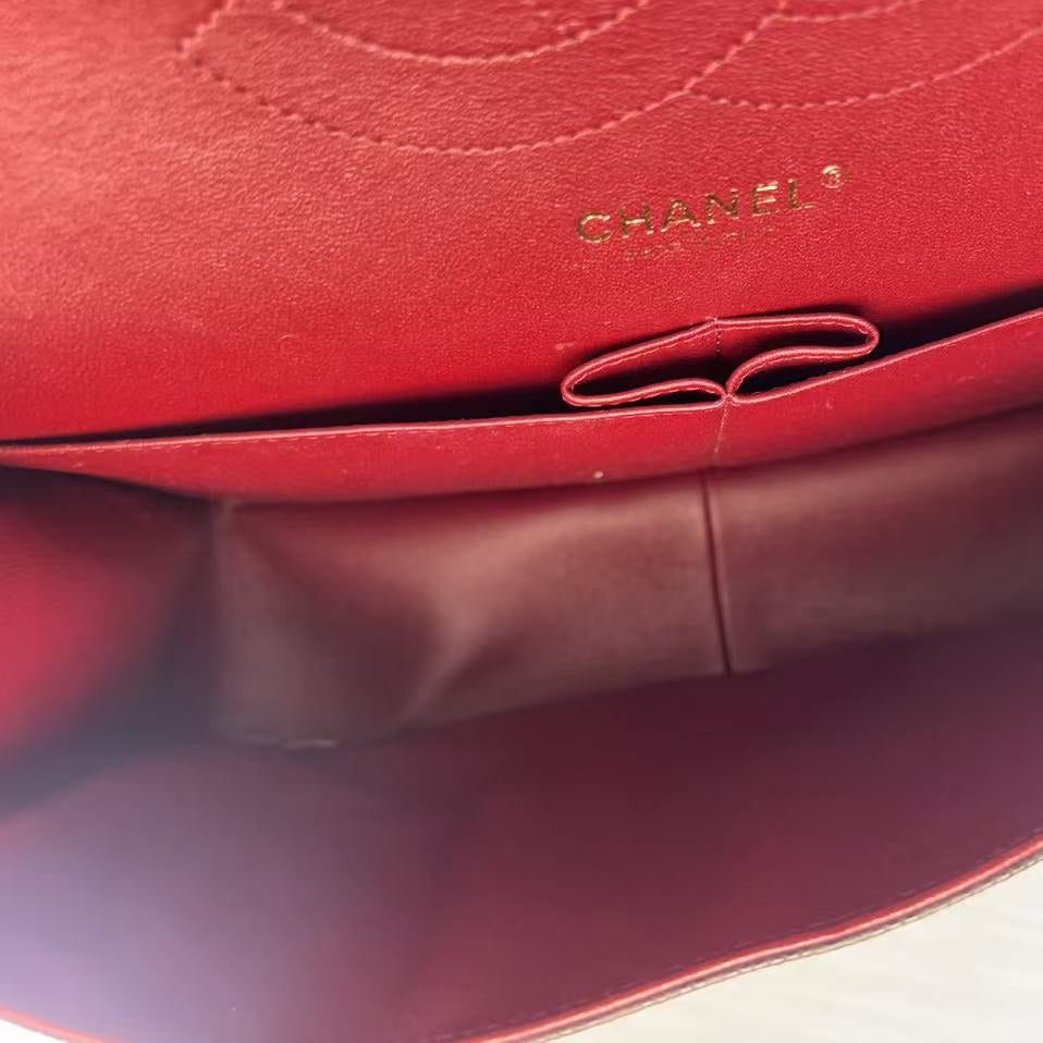 Close-up of the interior of a red Chanel handbag, showing the red leather lining, interior pocket, and embossed CHANEL PARIS logo.