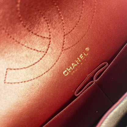 Close-up of a Chanel leather interior or pouch showing a stitched Chanel logo and gold CHANEL PARIS text on a warm reddish-brown leather surface.