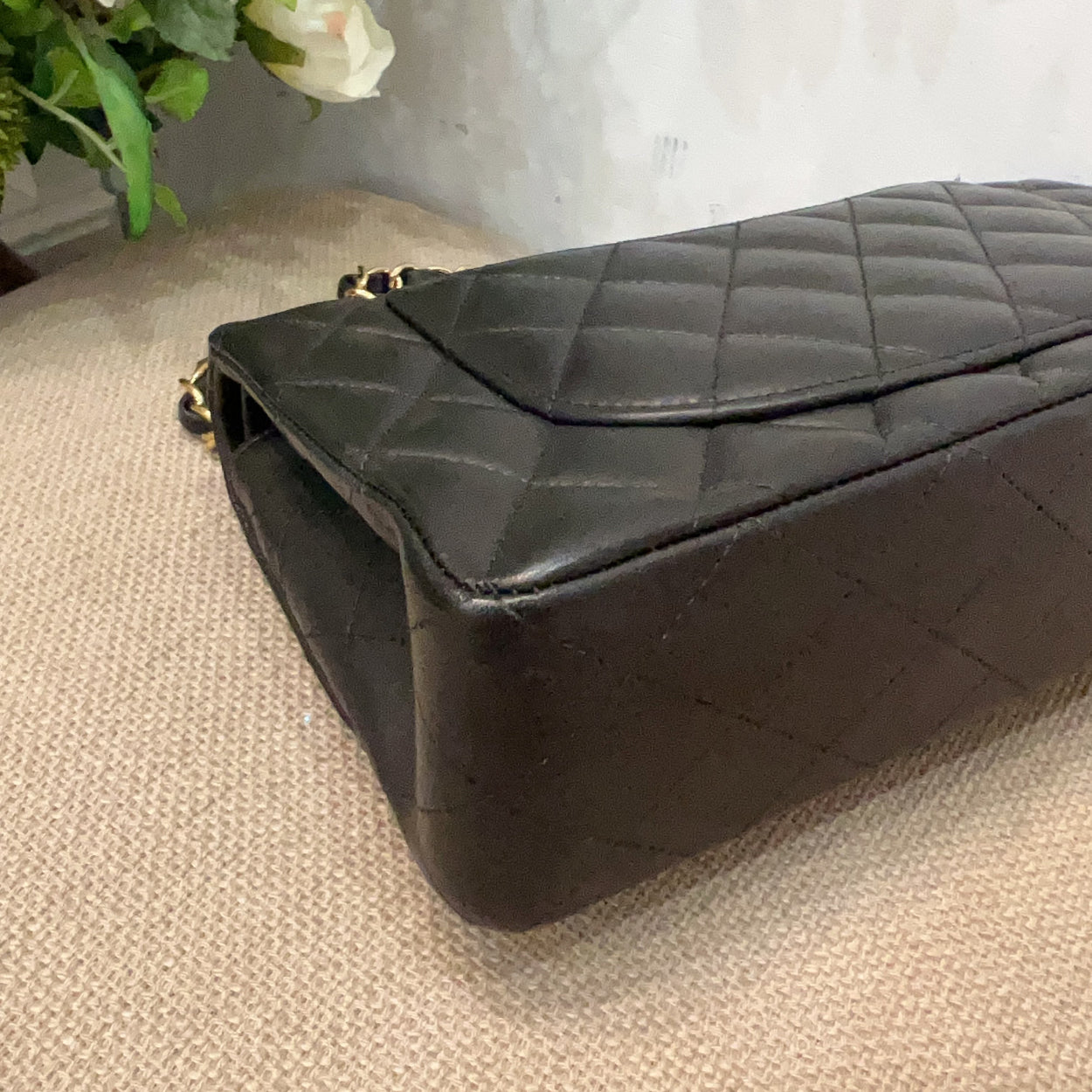 Black quilted handbag on a textured surface with a light background