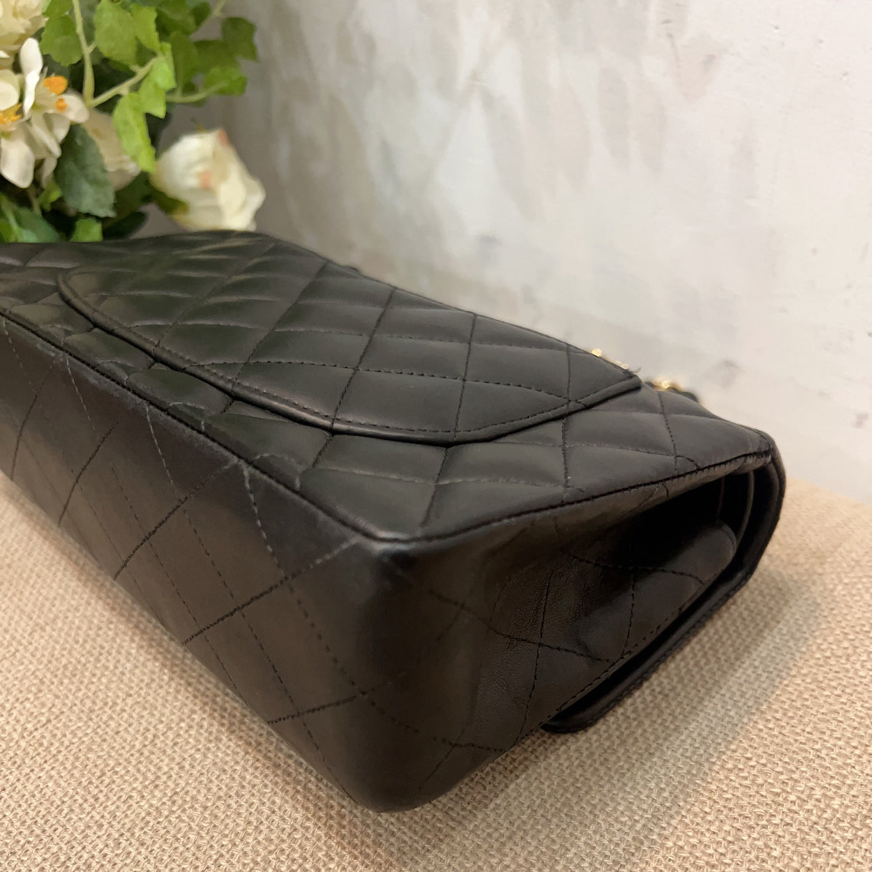 Black quilted handbag on a textured surface with a light background