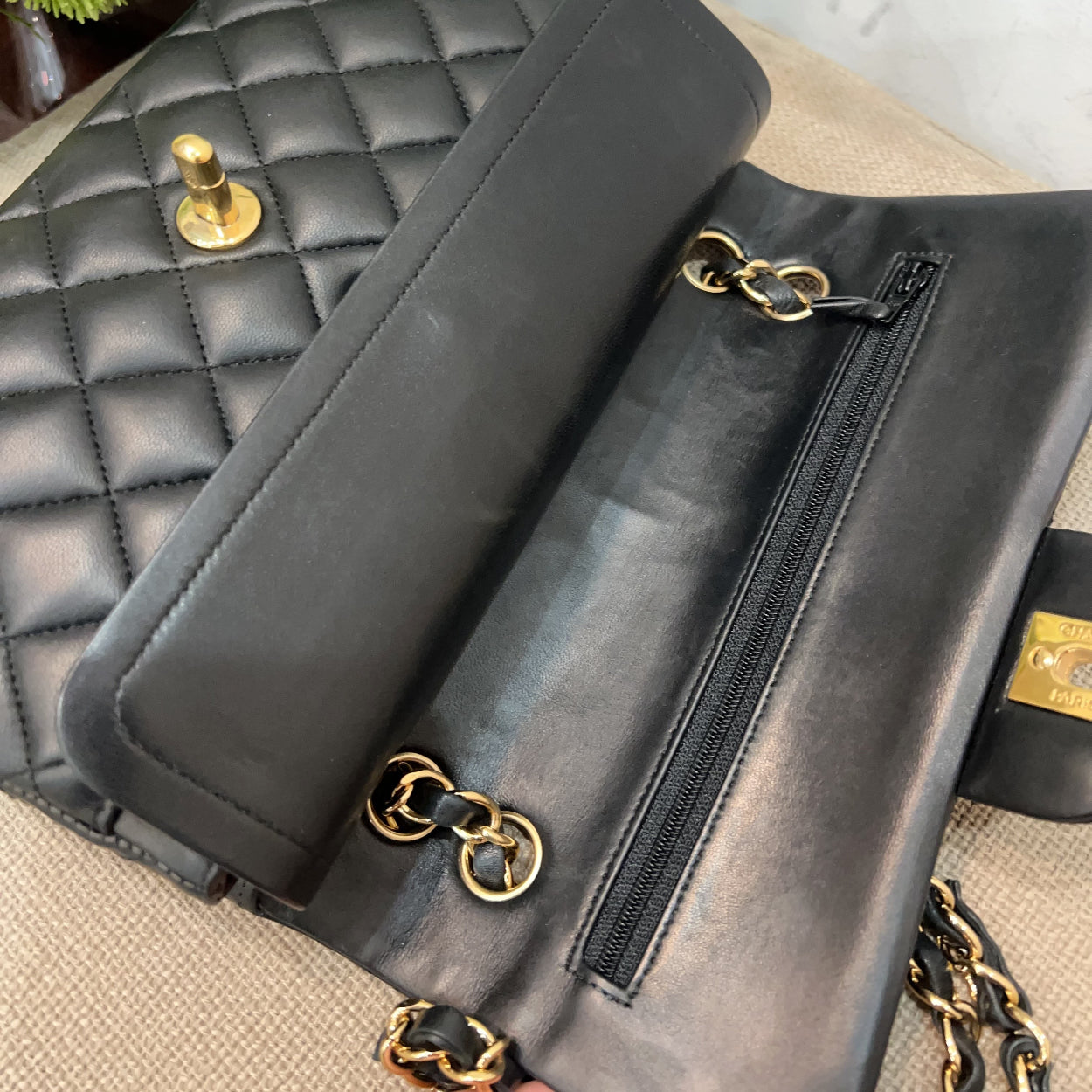 Black leather clutch with gold hardware on a textured surface with flowers in the background