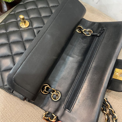 Black leather clutch with gold hardware on a textured surface with flowers in the background