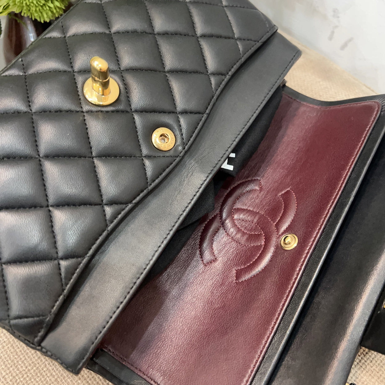 Black quilted handbag with gold hardware and a burgundy interior, featuring the Chanel logo.