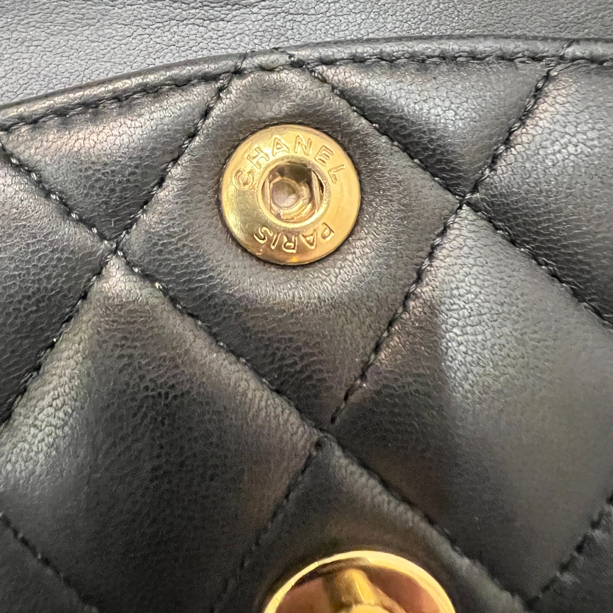 Close-up of a quilted leather handbag with gold buttons