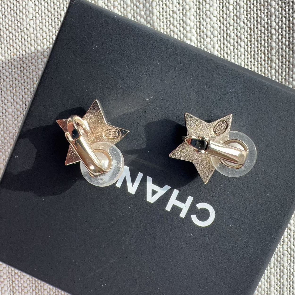 Gold star-shaped earrings on a black Chanel box